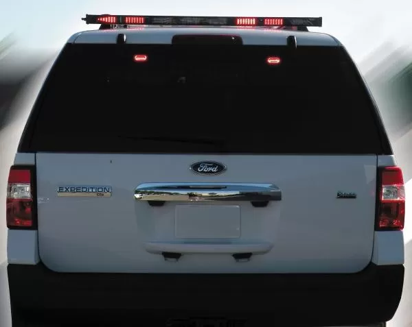 Rear of a white Ford Expedition with the roof-mounted arrow bar showing red segments illuminated