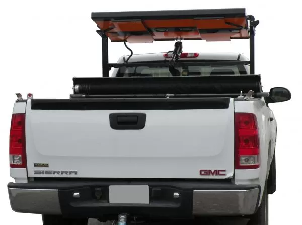 Board folded flat in its stowed position on the rack above the pickup cab, seen over the tailgate