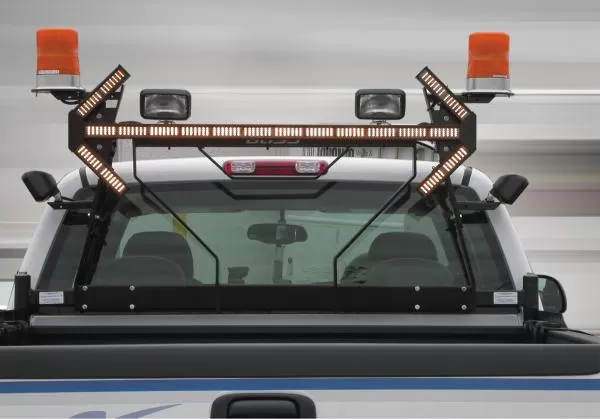 Amber light stick lit on the cab rack of a white truck between two rotating beacons and work lights