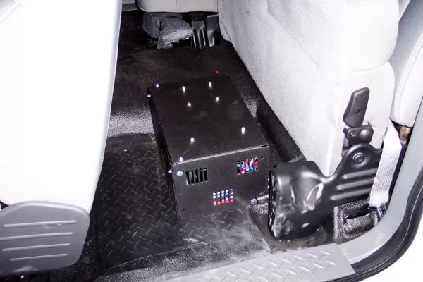 Unit bolted to the rear floor of a cruiser with a fuse strip and wiring connectors on the end panel