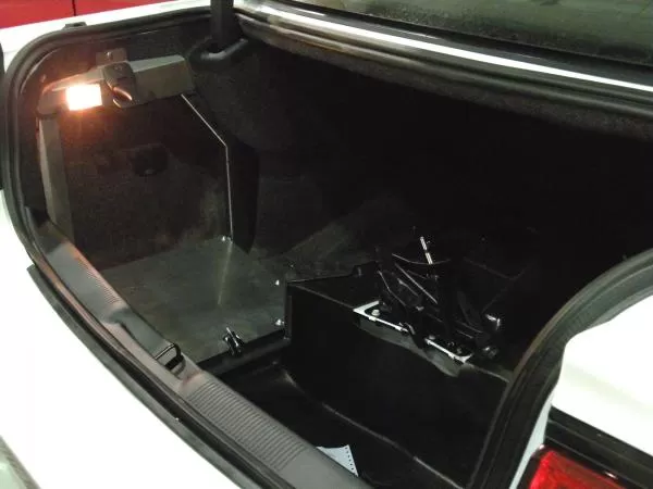 Door swung open in the trunk, exposing the mounting space behind it and the spare tire well