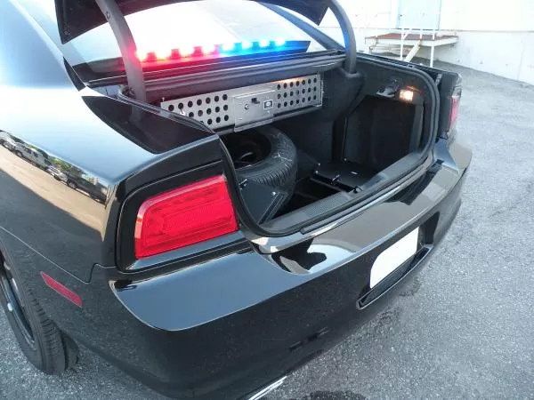 Black Charger with the trunk open, perforated equipment panel inside and the rear lightbar lit red and blue