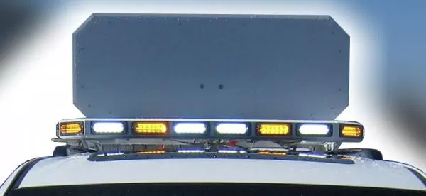 Blank back of the raised sign panel seen from behind the roof, lightbar below flashing amber and white