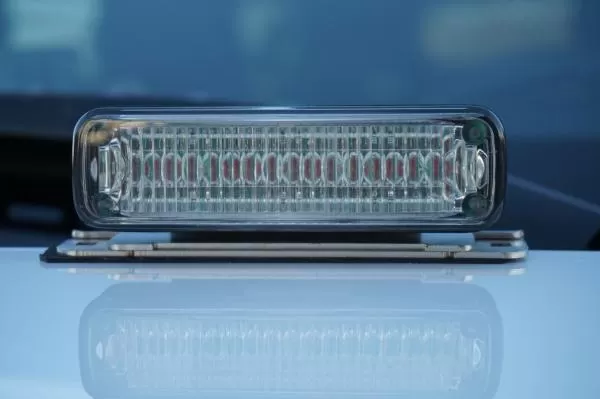 Straight-on look at a deck mounted clear module, lens optics and low bracket reflected in the white paint