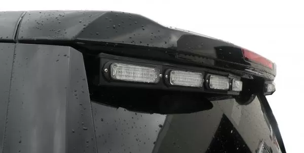 Close-up of the unlit clear lenses in their black bracket under the spoiler edge of a Chevy Tahoe