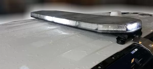 Bar on a white roof with clear lenses and white LEDs showing, low profile against a wet painted panel