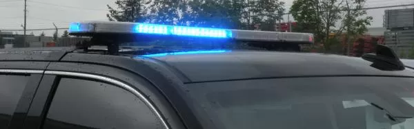 Blue LED modules flashing the full length of the bar on the roof of a black SUV in daylight