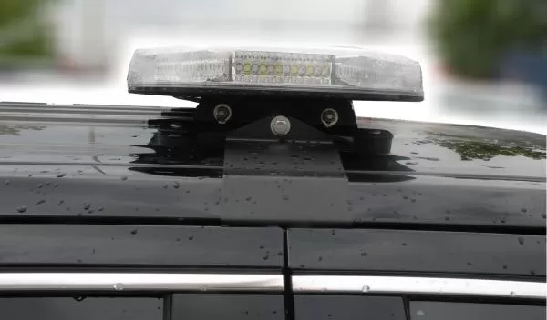Close-up of a compact bar on its bolted roof bracket, white LEDs visible through the clear lens