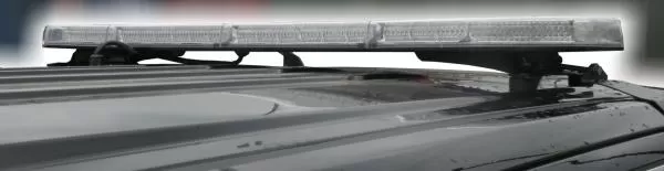 Unlit bar seen from the side on a vehicle roof, showing the low-profile lens and its roof mounting feet
