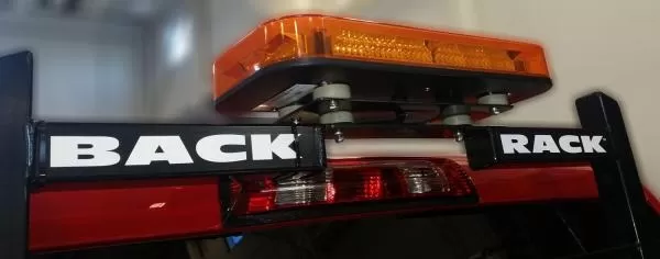 Close-up of the bar bolted to the rack crossbar on rubber isolator feet, amber lens unlit
