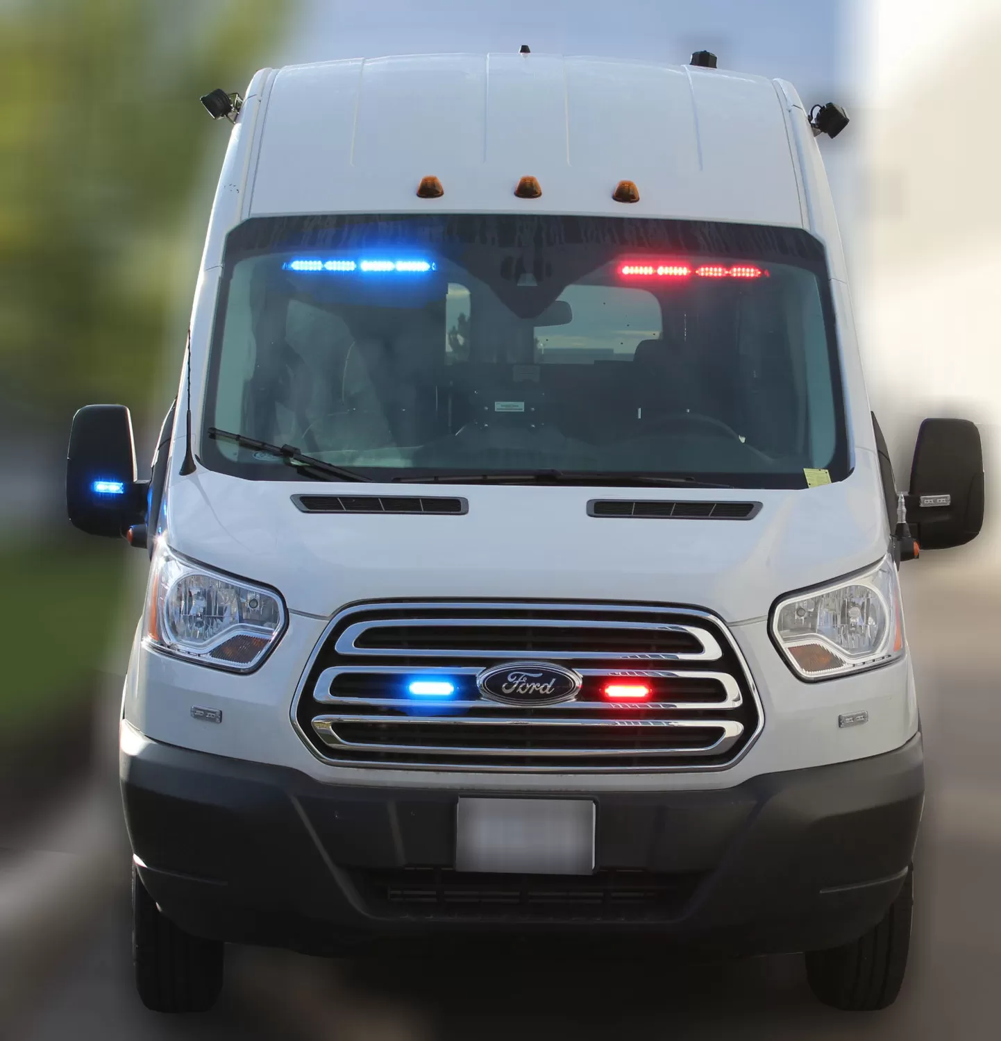 White Ford Transit van with the visor bar lit blue on the left and red on the right behind the windshield
