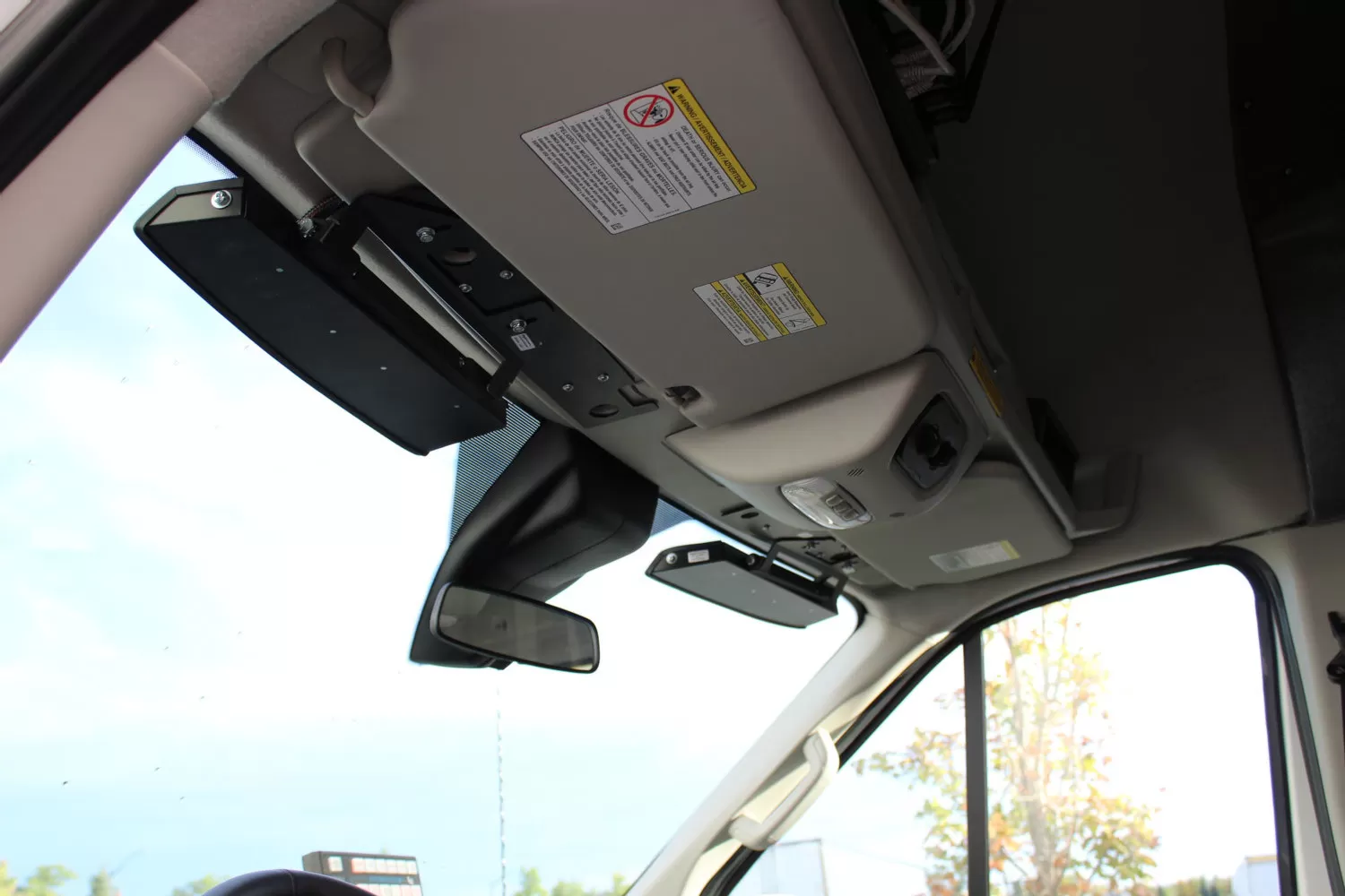 Looking up at a Transit windshield header where the black bar bracket sits beside the sun visor