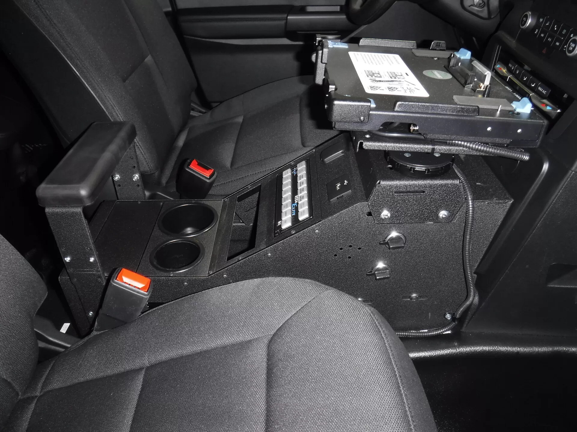 Console installed with a laptop dock on its swing arm, breaker panel and two cup holders below
