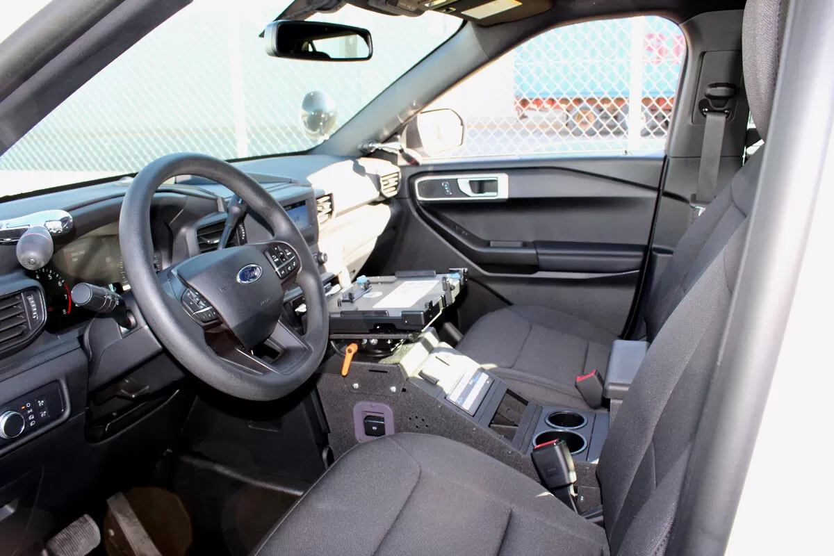 Console fitted in a white Ford SUV, empty dock plate ahead of the cup holders and 12V outlet