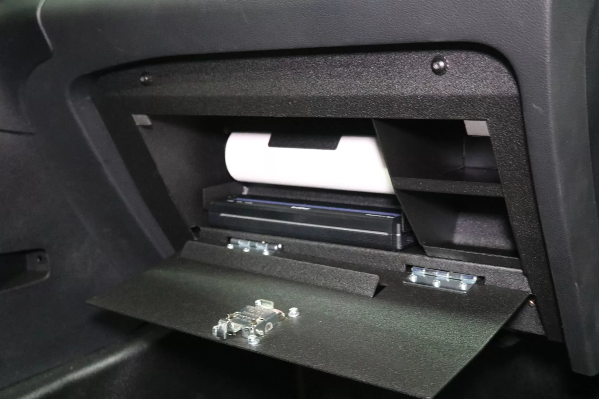 Close view of the open glove box with the paper roll above the printer and the door latch strikes