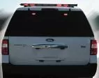 Rear of a white Ford Expedition with the roof-mounted arrow bar showing red segments illuminated