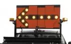 Close-up of the orange reflective panel with the left arrow lit in amber and a beacon on each rack corner