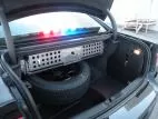 Trunk interior with the perforated aluminum equipment panel mounted above the spare tire, lightbar lit