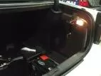 Driver side of a white Charger trunk with the door closed, brass key lock and dome light switched on