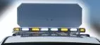 Blank back of the raised sign panel seen from behind the roof, lightbar below flashing amber and white