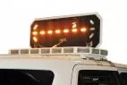 Motorized board tilted up on its arms with one amber arrow lit and the lift mechanism visible underneath