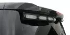 Close-up of the unlit clear lenses in their black bracket under the spoiler edge of a Chevy Tahoe