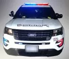 Front of a white Ford Explorer police unit with the roof bar, grille and bumper LEDs flashing